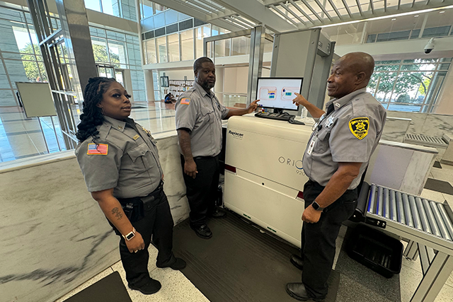 Three Security Guards Using Equipment in a Modern Building Lobby